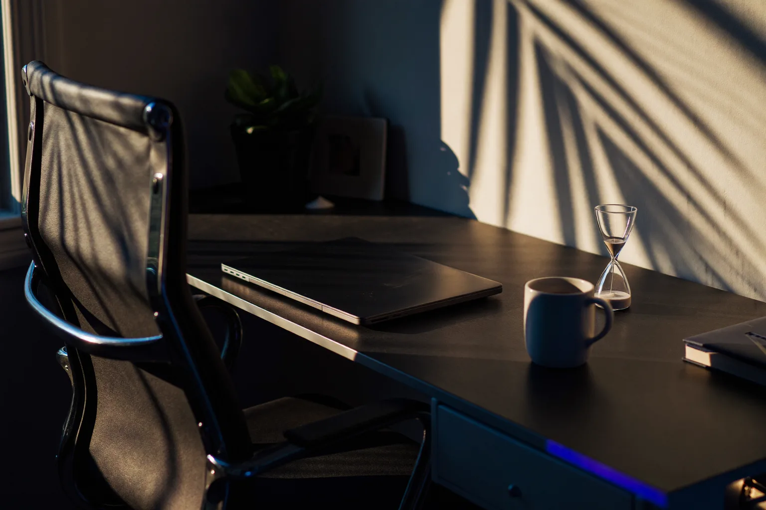 A sunlit California home office left empty for a break: chair pushed back, laptop closed, a mug still steaming
