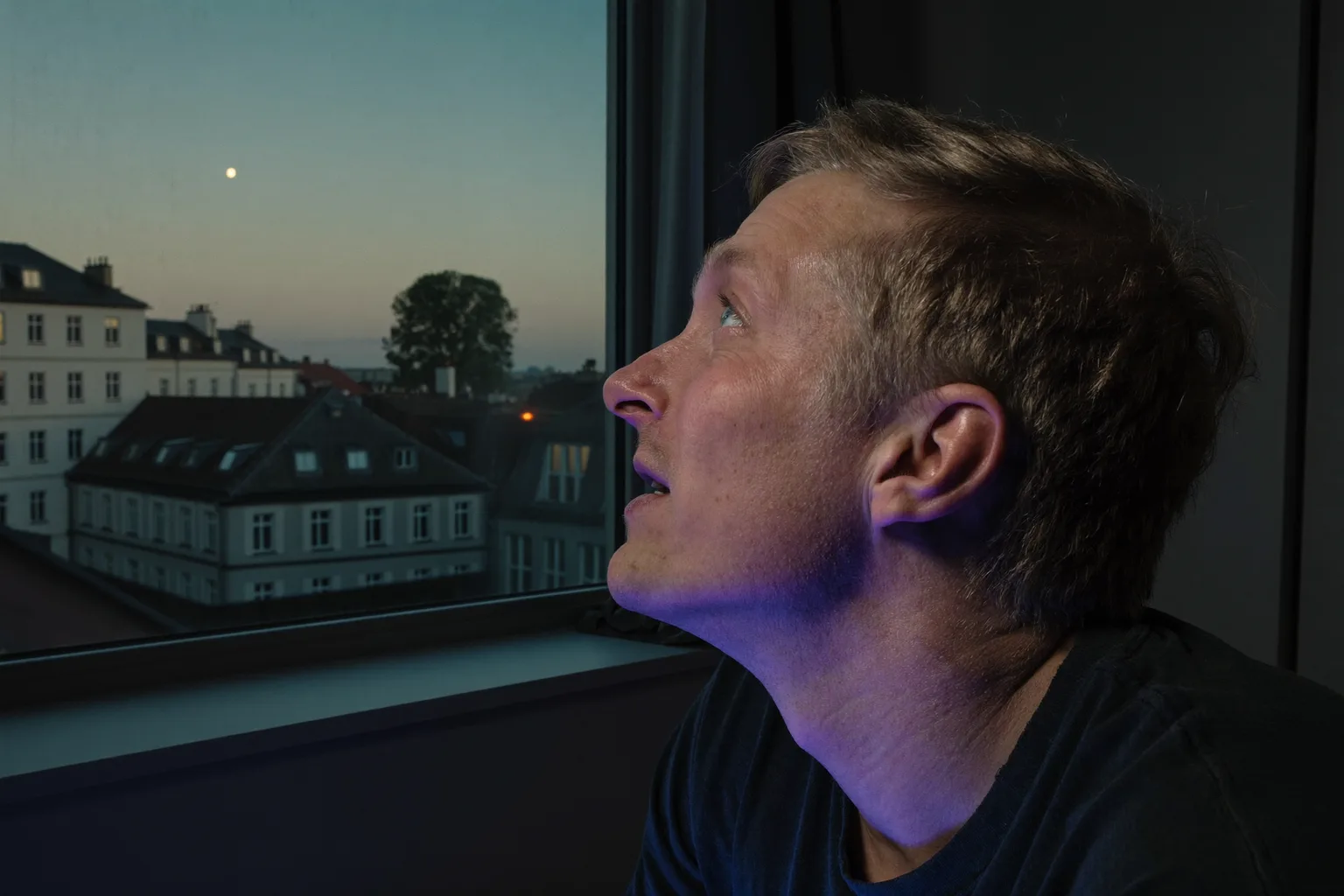 Person am Bildschirm wendet die 20-20-20-Regel gegen müde Augen an: Blick vom Laptop weg, aus dem Fenster zu einem entfernten Baum