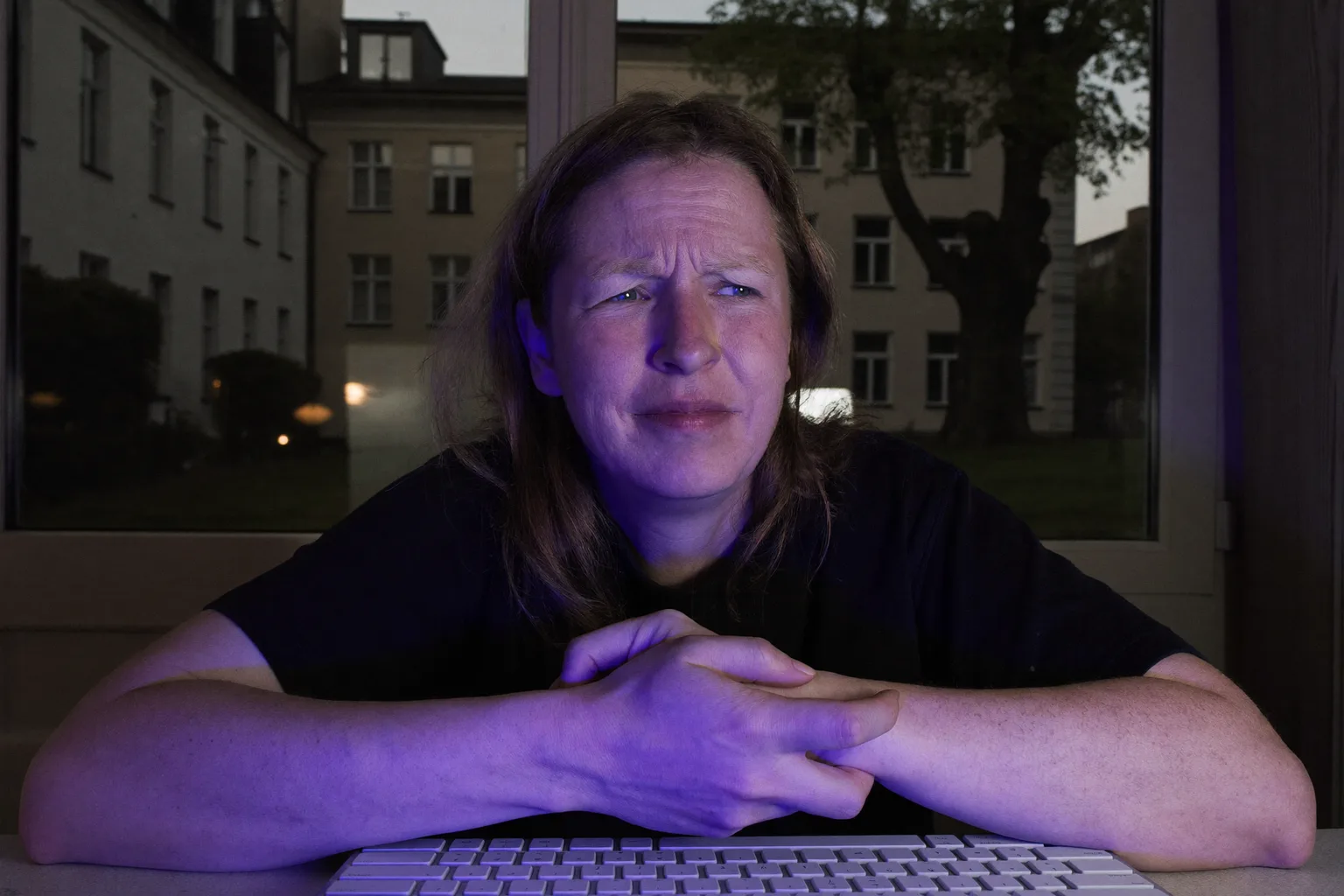 Eine Person am Schreibtisch hält mit der anderen Hand das rechte Handgelenk, Tastatur davor, sichtbar die taube, schmerzende Hand bei Karpaltunnelsyndrom-Symptomen