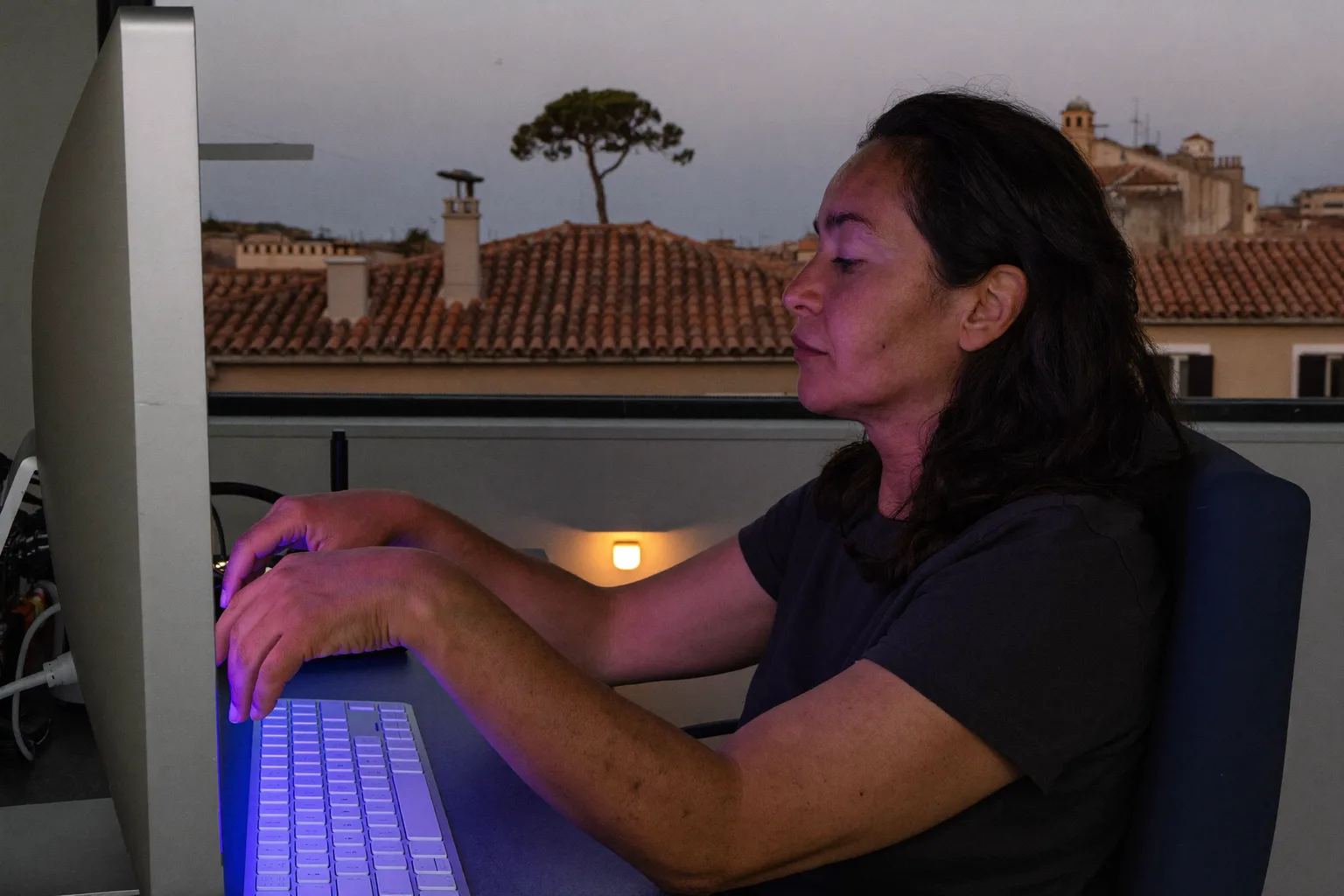 Una persona vista de perfil sentada en un escritorio, con los pies apoyados en el suelo, la espalda contra el respaldo, los antebrazos a la altura de la mesa y el monitor a la altura de los ojos: la postura de referencia en el escritorio