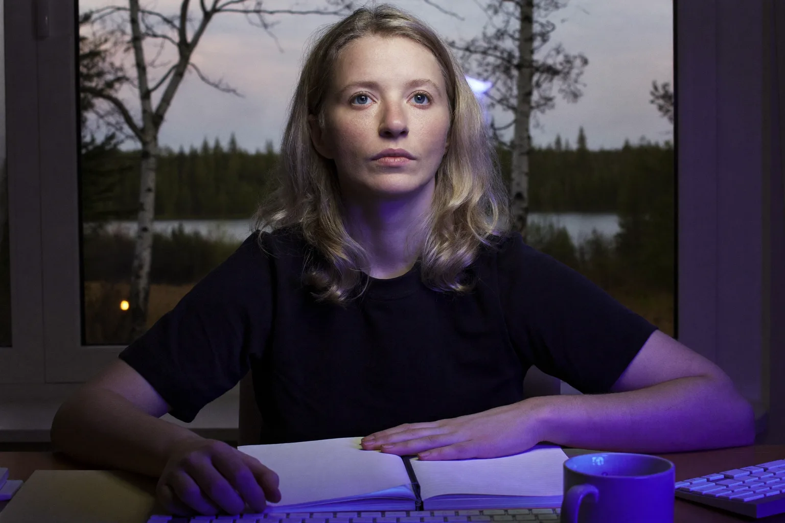 Näyttötyöläinen noudattaa 20-20-20-sääntöä silmärasitusta vastaan, katsoen pois kannettavasta tietokoneesta ikkunasta ulos kohti kaukaista puuta
