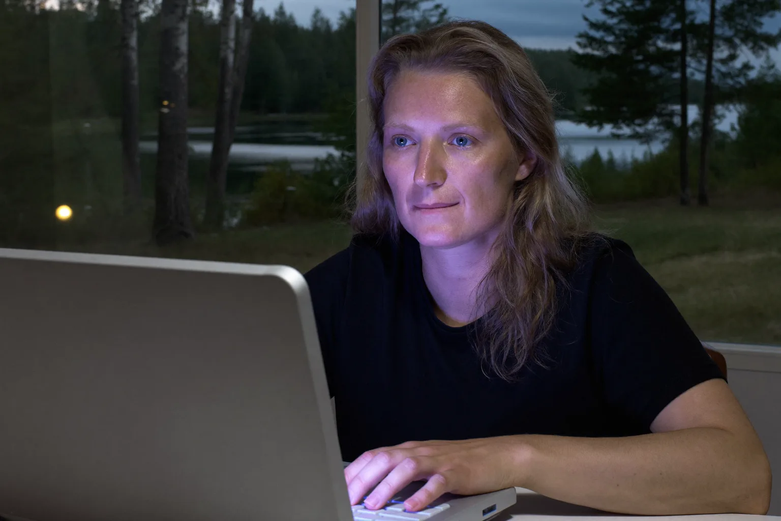 Henkilö istuu kotitoimistollaan myöhään illalla, katse tuijottaa kannettavan näytön ohi kädet yhä näppäimistöllä, kasvoilla työuupumuksen tyhjä väsymys