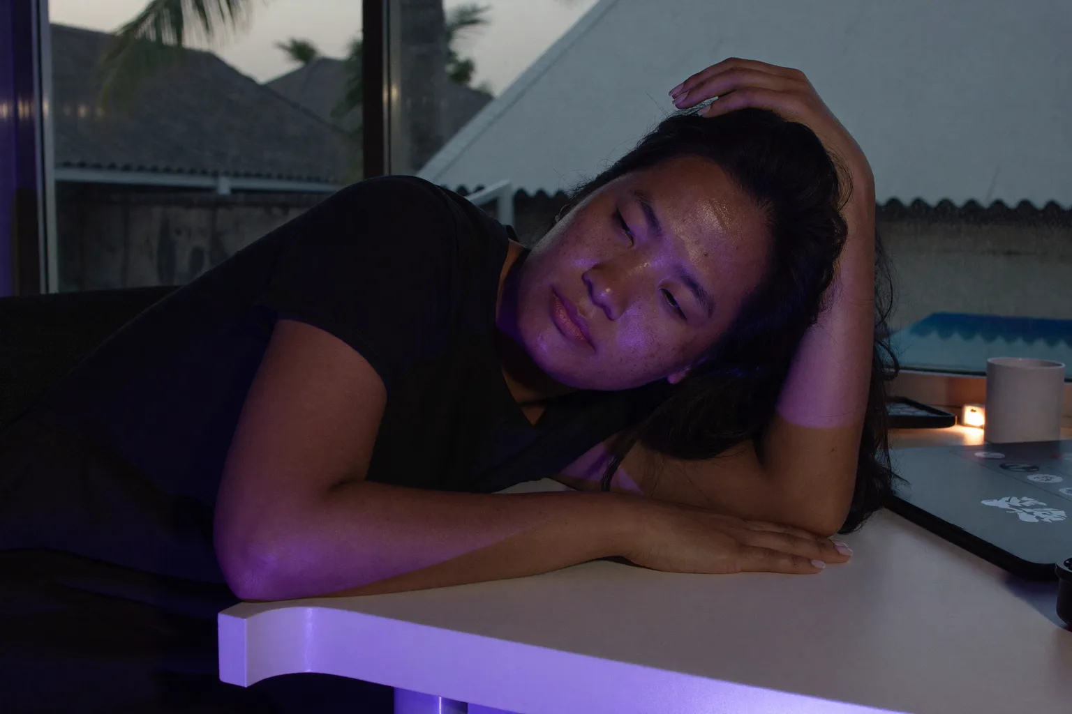 Isang tao sa home desk nang gabing-gabi na, nakatungo ang ulo papunta sa isang kamay na nasa buhok, mababa at unfocused ang tingin, at hindi gumagalaw ang isang braso sa ibabaw ng walang laman na mesa