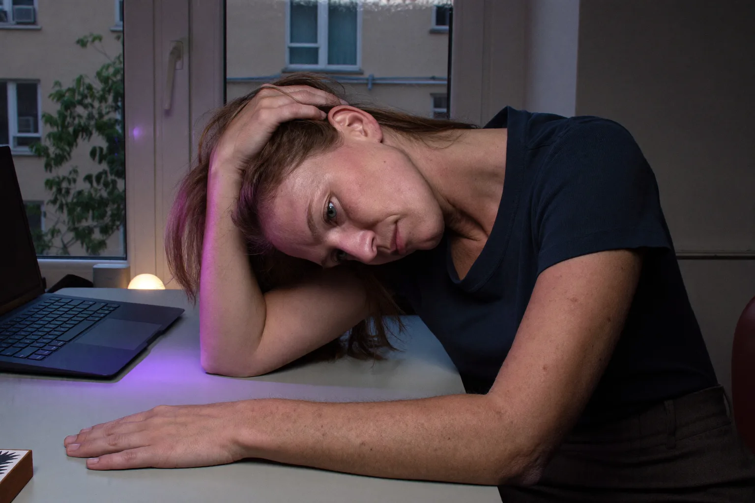 Egy ember késő este otthoni íróasztalánál ül, fejét az egyik kezébe hajtja, ujjai a hajában, tekintete lesütött és révedező, a másik alkarja mozdulatlanul fekszik az üres asztalon