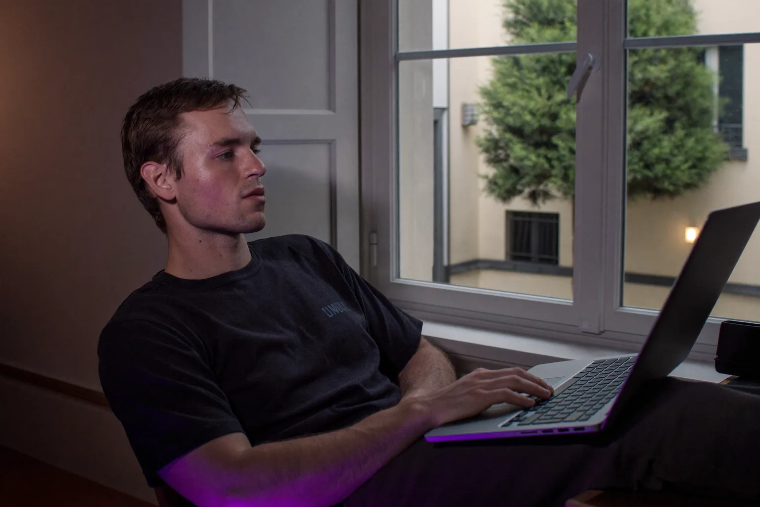 Egy távmunkás megáll otthoni íróasztalánál, hogy kinézzen az ablakon, távol a laptoptól