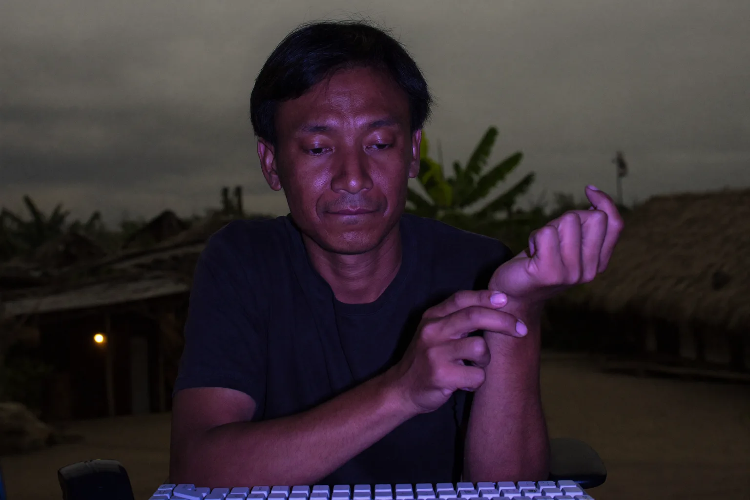 Seseorang di meja kerja memegang pergelangan tangan kanannya dengan tangan yang lain, keyboard di depannya, menunjukkan tangan yang kebas dan nyeri akibat gejala carpal tunnel syndrome