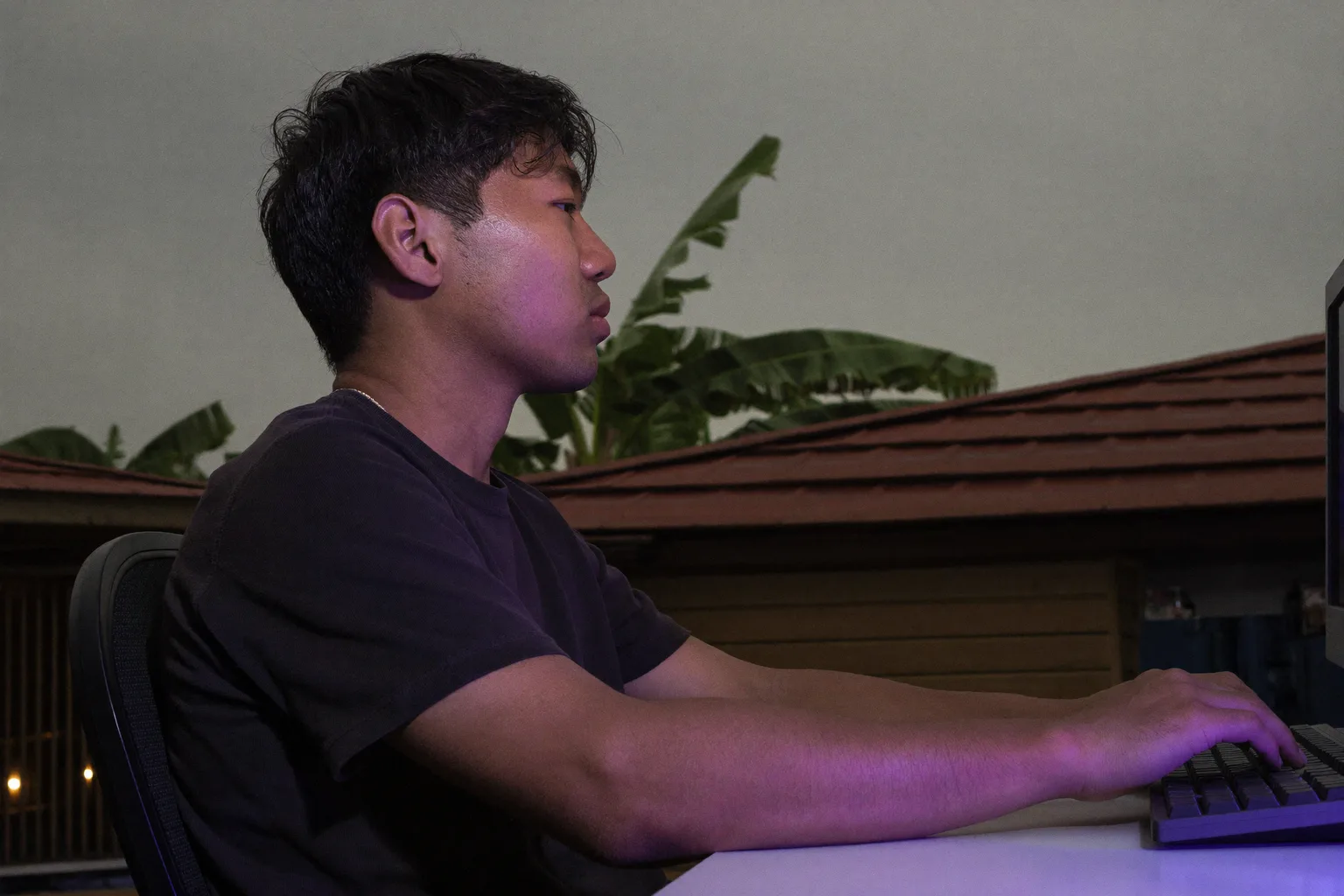 Seseorang dilihat dari samping duduk di meja kerja dengan kaki rata di lantai, punggung bersandar pada sandaran kursi, lengan bawah sejajar dengan meja, dan monitor sejajar mata, postur meja kerja acuan