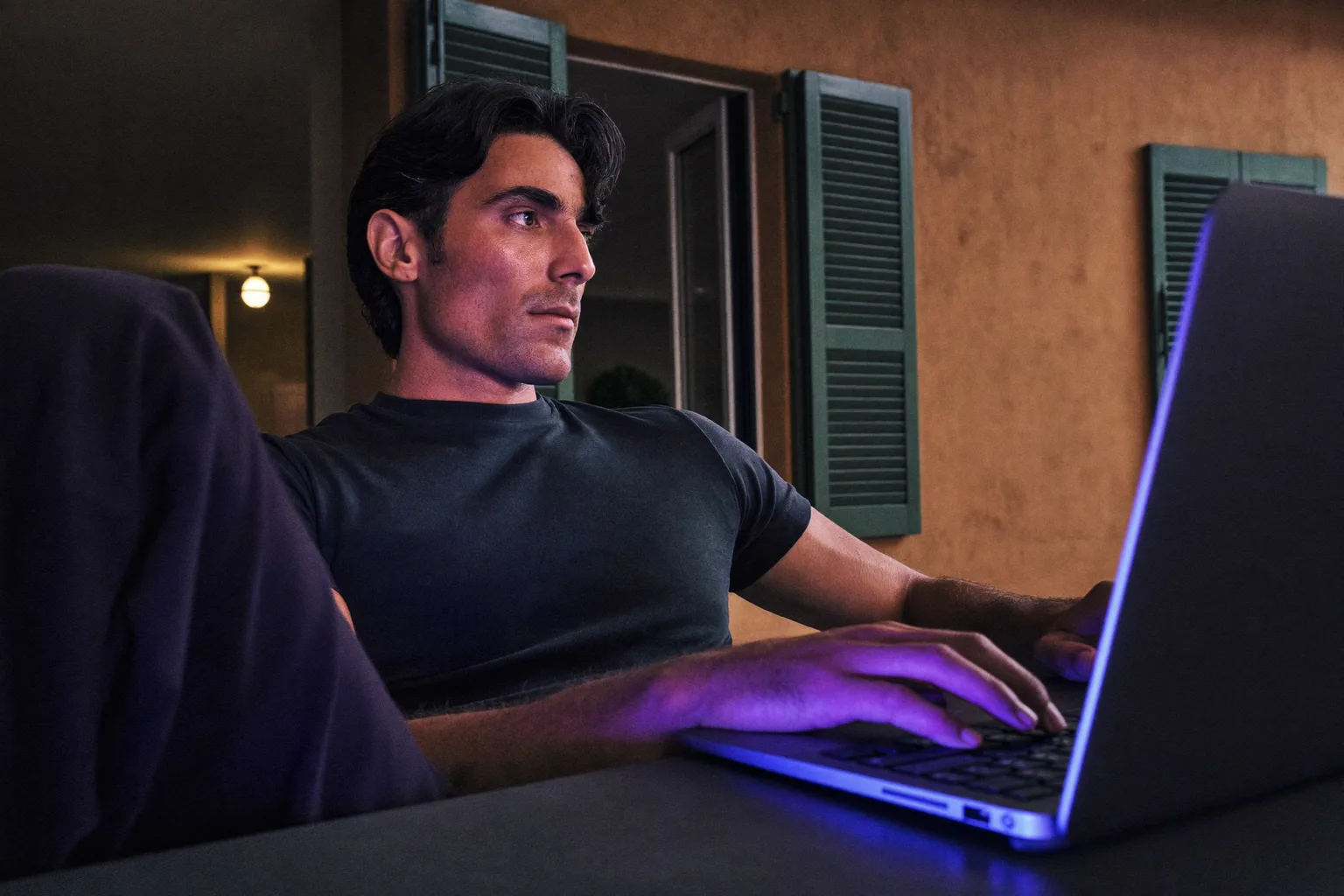 Una persona in smart working che si ferma alla scrivania di casa per guardare fuori dalla finestra, lontano dal laptop