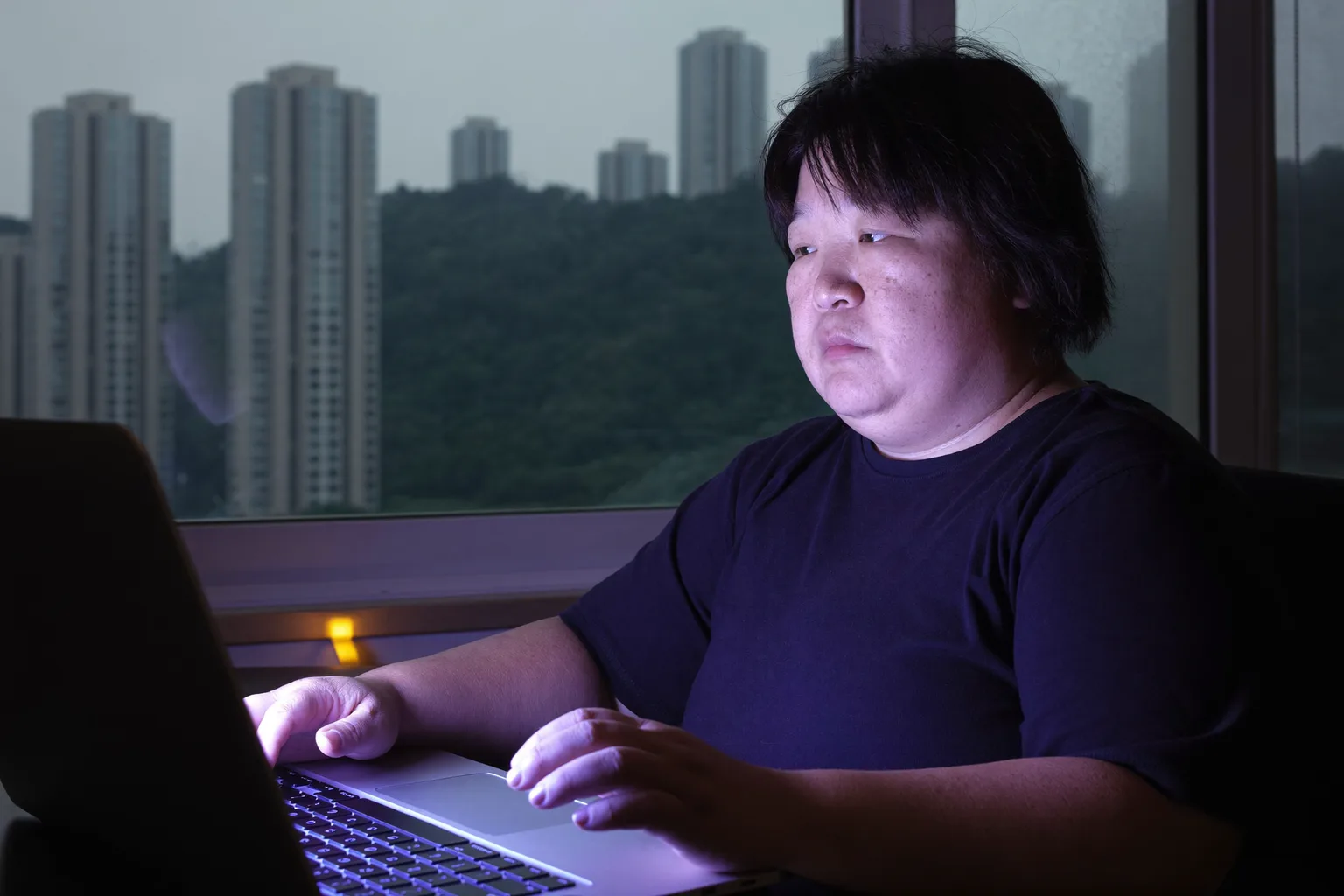 늦은 저녁 집 책상 앞, 손은 키보드 위에 그대로 둔 채 노트북 화면 너머를 멍하니 바라보는 사람. 직장 번아웃 특유의 무기력한 탈진을 보여주는 모습