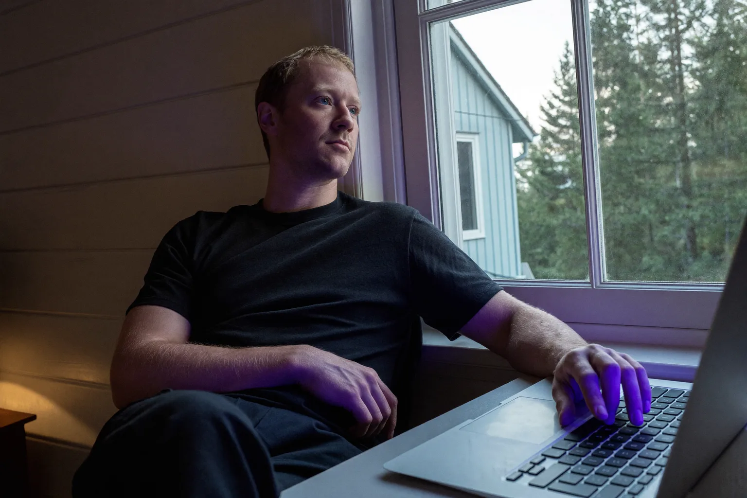 En som jobber hjemmefra tar en pause ved hjemmekontoret for å se ut vinduet, bort fra laptopen