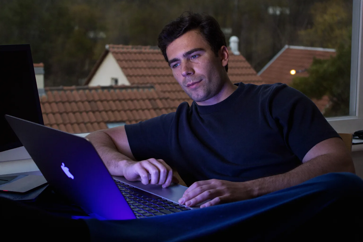Un angajat care lucrează de acasă face o pauză la birou și privește pe fereastră, departe de laptop