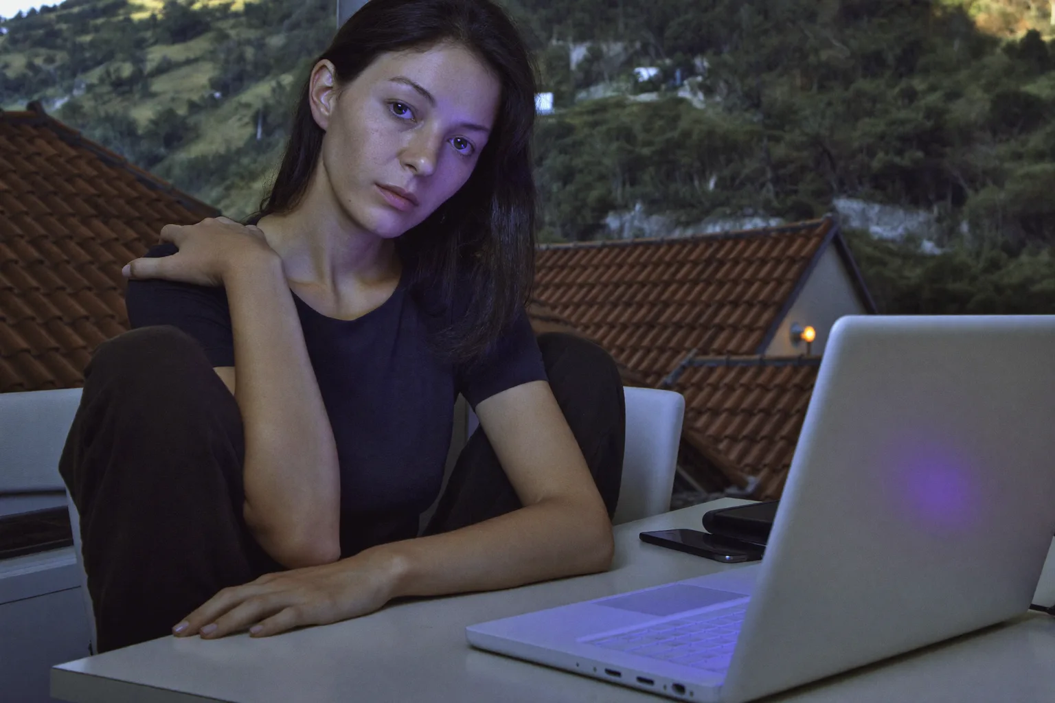 O persoană la birou care își duce mâna la baza gâtului să și-l maseze, în fața unui laptop, arătând gâtul înțepenit și dureros după o zi lungă la calculator