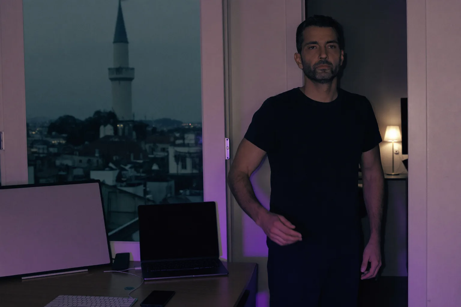 Akşam vakti, ışığı yanan bir odada ev masasında kapalı duran bir dizüstü bilgisayar ve uzaklaşan kişi: evden çalışma gününün sona erdiğini gösteriyor