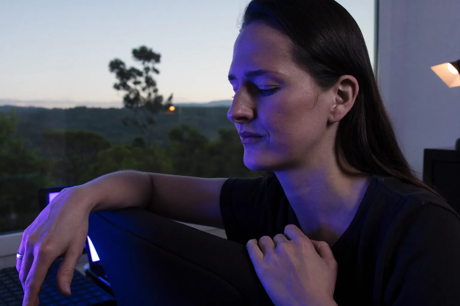 A remote worker pausing at their home desk to look out the window, away from the laptop