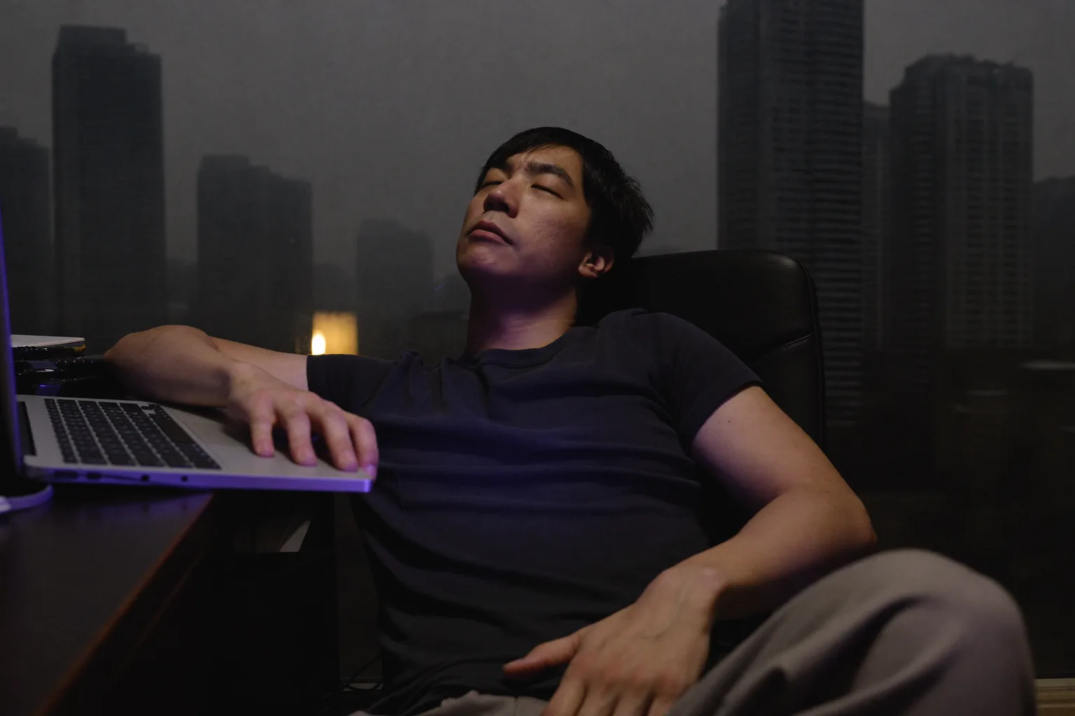 一位居家办公的人在家中书桌前暂停下来,把视线从笔记本电脑移开,望向窗外