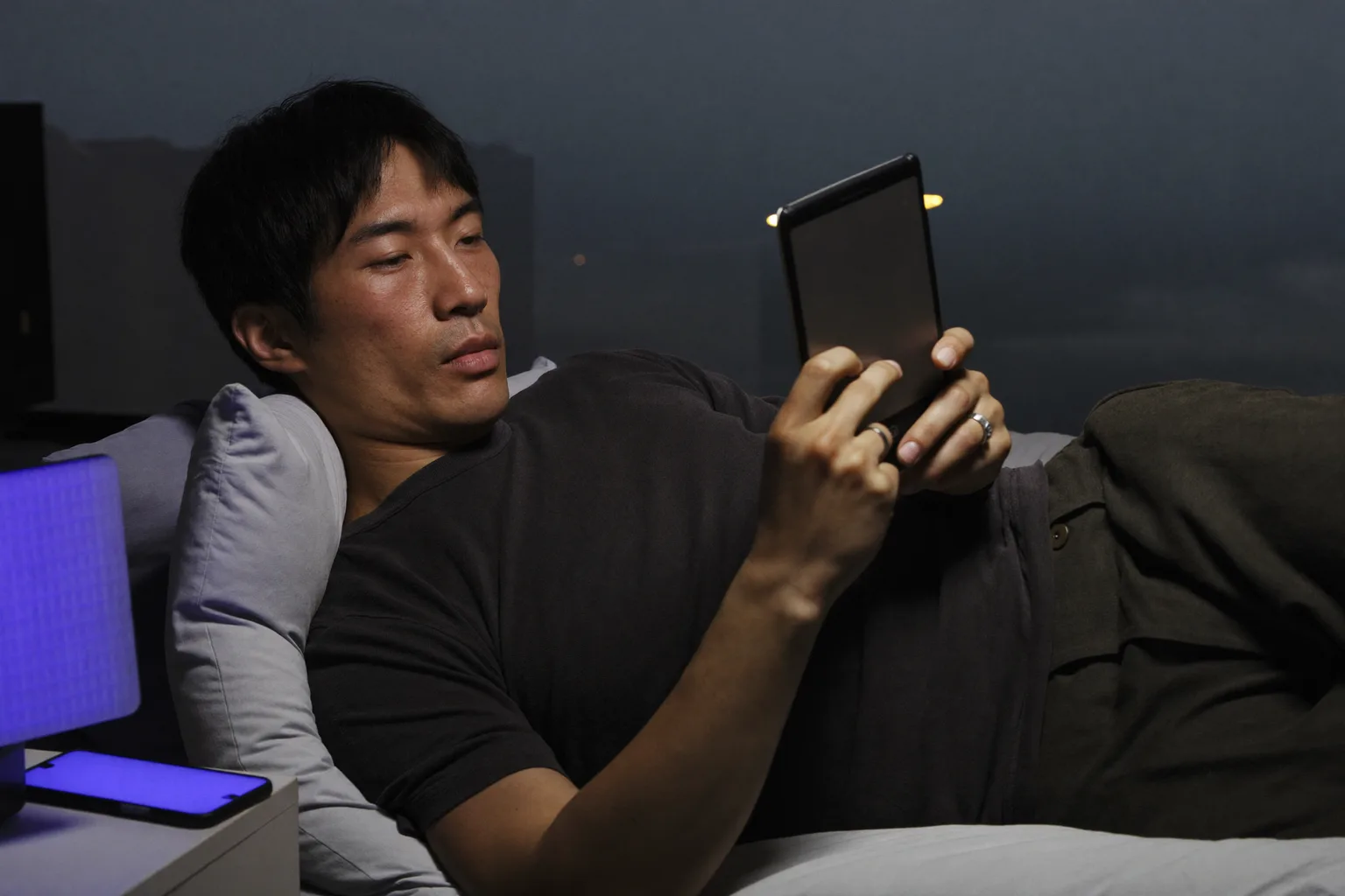 深夜，一名男子躺在床上用電子書閱讀器看書，頁面透出的微光幾乎照不到臉上，而床頭櫃上一部螢幕朝上的手機，把旁邊那盞燈罩染成一片生硬冰冷的藍光