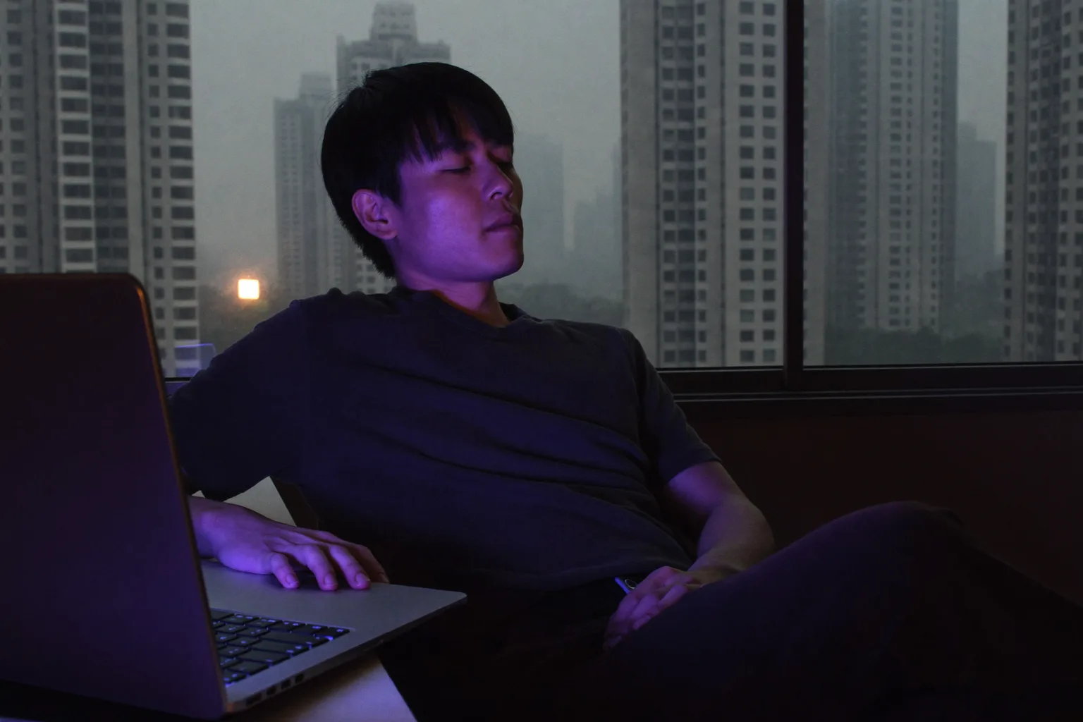 遠距工作者在家中書桌前暫停工作,望向窗外,遠離筆電畫面